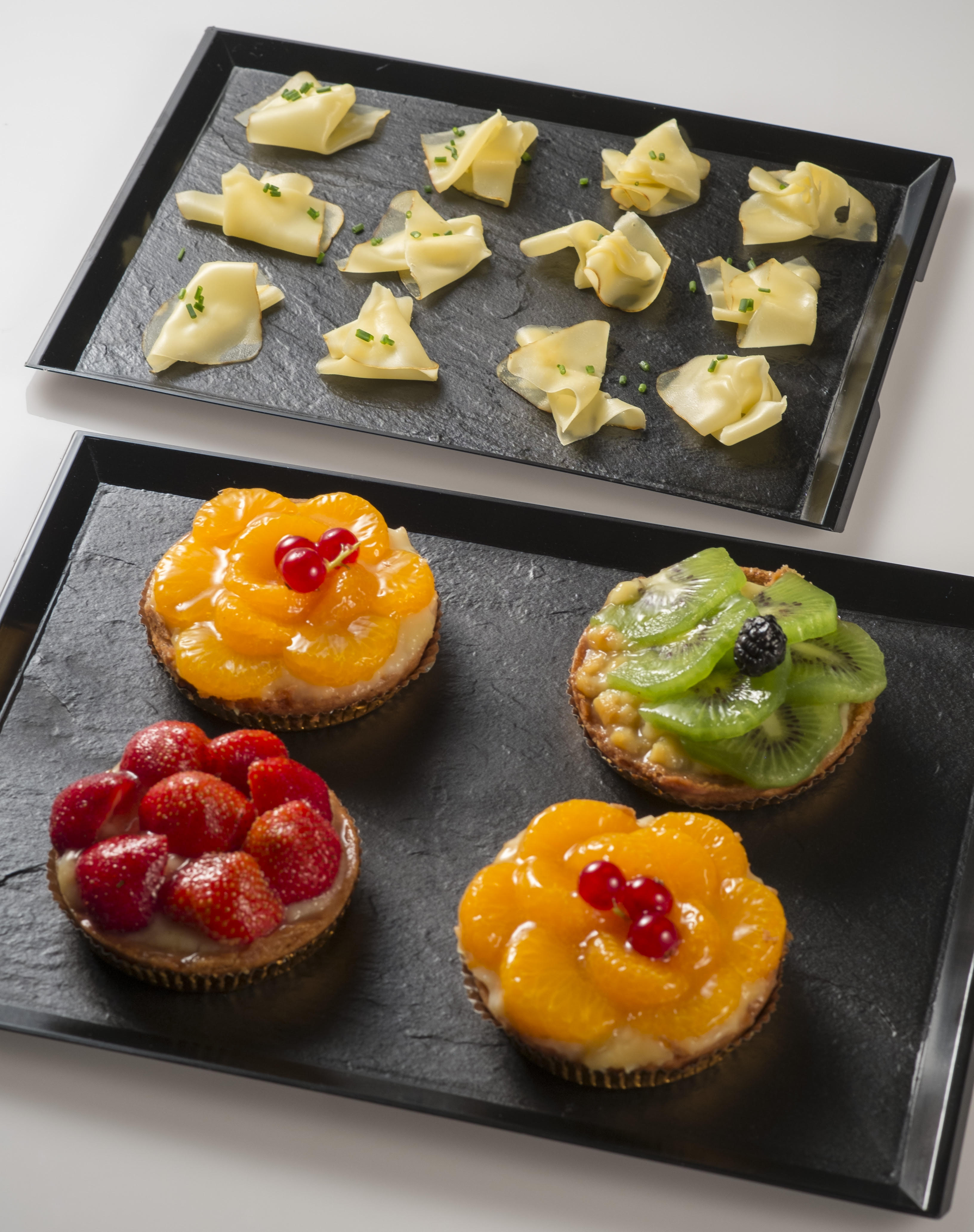 Bandejas efecto pizarra con canapés de queso y tartaletas de fruta para catering