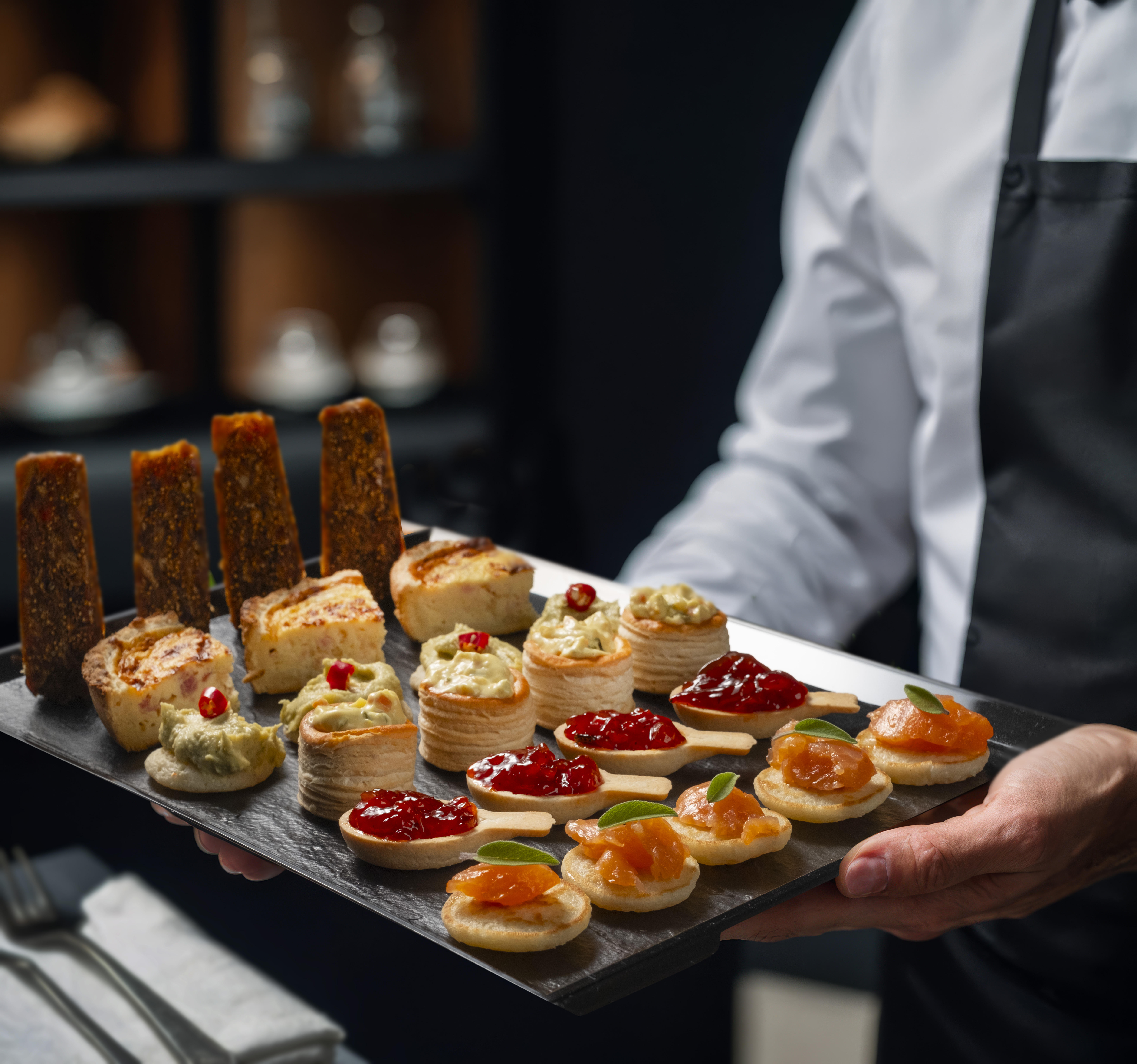 Camarero sirviendo aperitivos en bandeja efecto pizarra para catering profesional